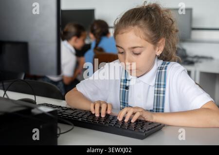 Elementary School Girl Typing on Computer Keyboard in class Stock Photo