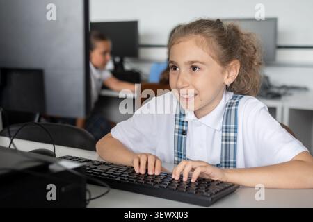 Elementary School Girl Typing on Computer Keyboard in class Stock Photo
