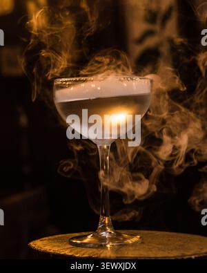 Signature smoked cocktail with dramatic vapor in an elegant cocktail glass. Stock Photo
