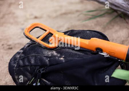Person scanning sand with a compact metal detector probe Stock Photo