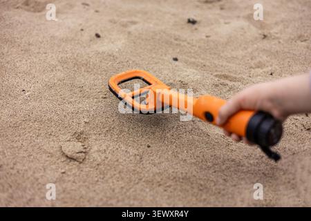 Orange pinpointer metal detector resting on a black backpack Stock Photo