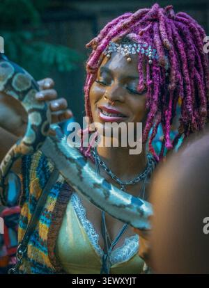 Happy woman with pink dreadlocks holding a snake Stock Photo