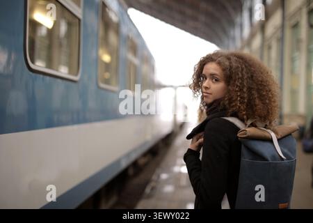 Woman with backpack looks back on platform Stock Photo