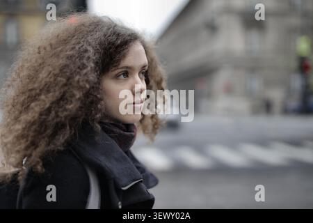 Young woman with curly hair waiting on a city street Stock Photo