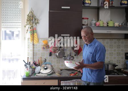 Senior man doing chores in a sunlit kitchen Stock Photo