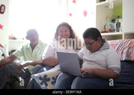 Boy using laptop with proud family watching Stock Photo