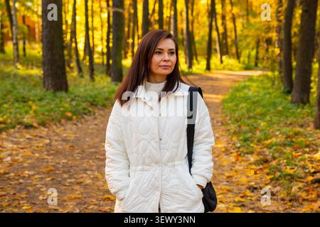 Successful 42 year old woman architect walking in beautiful autumn park. Professional designer taking a stroll in nature. Lifestyle portrait of mature Stock Photo