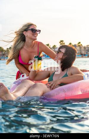 Two young women enjoying summer vacation in swimming pool Stock Photo