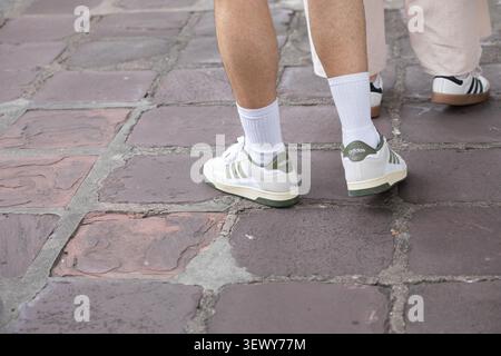 BANGKOK, THAILAND - JUN 3, 2026: Man in white Adidas sneakers, high angle view. Stock Photo