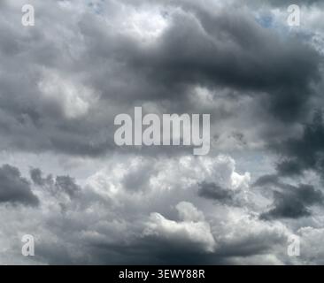 Close up of a sky full of dark storm clouds with a small patch of blue sky near the top Stock Photo