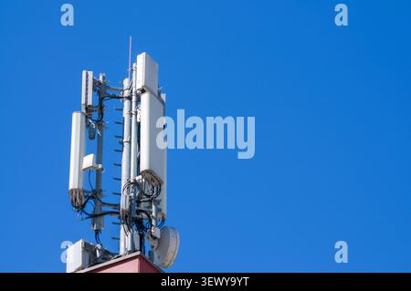 Low angle view of a modern telecommunication tower with 5G and 4G cellular antennas against a clear blue summer sky background. Mobile phone network i Stock Photo