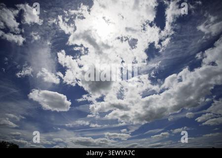Puffy white Cumulus clouds with the sun beating trhough them on a bright summers day. Stock Photo