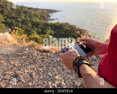Person using drone camera overlooking coastal landscape during outdoor adventure Stock Photo