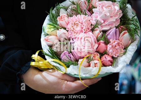 Bright Floral Bouquet Handoff. Courier Presenting Vibrant Pink Flowers Wrapped With Yellow Ribbon Stock Photo