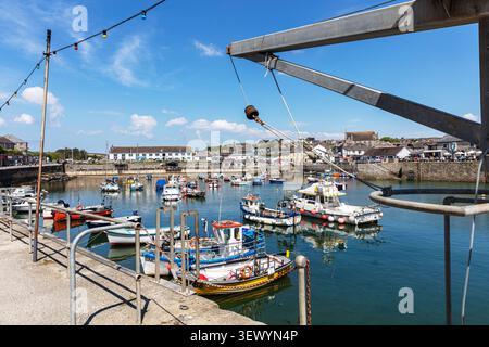 harbour scene at Porthleven, Cornwall, with colourful fishing and leisure boats floating on calm water beside the stone harbour walls. Waterfront buil Stock Photo