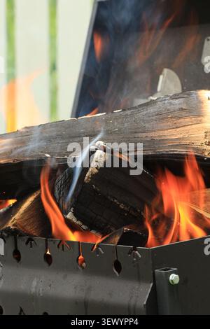 Vertical photo with blackened and burning wood stacked in a brazier Stock Photo
