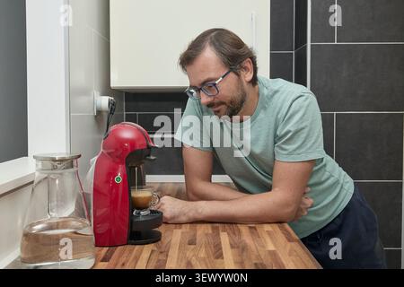 Man making coffee with coffee machine in modern kitchen. Person preparing espresso at home and enjoying a fresh cup of coffee. Concept of morning rout Stock Photo