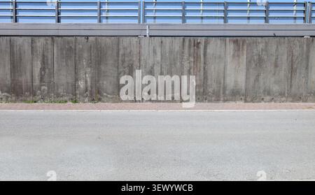 Prefab concrete boundary wall with a safety rail on top. Red sidewalk and street in front. Background for copy space. Stock Photo