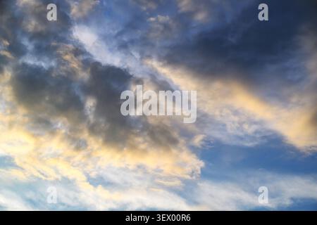 Dramatic sky with dark clouds and golden sunlight breaking through Stock Photo