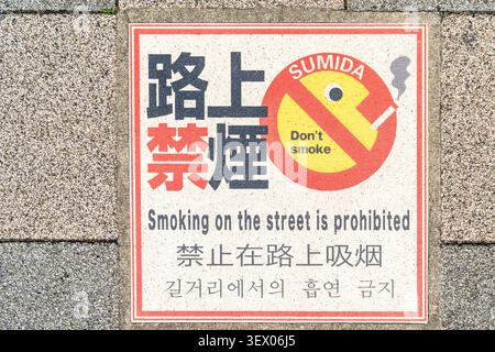 Bilingual sign on the pavement in the Sumida ward of Tokyo, 'Don't smoke. Smoking on the street is prohibited.' In both English and Japanese. Stock Photo
