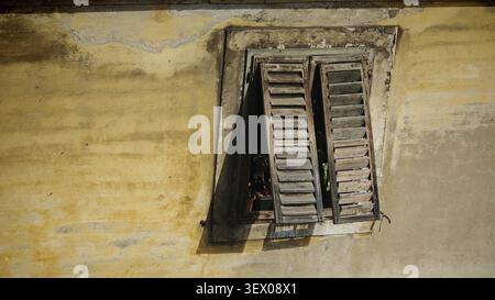 Weathered shutters on a yellowish building in close-up with light penetrating, Rijeka, Croatia Stock Photo