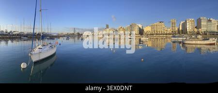 Boats in Malta, Marina with sailboats and city skyline reflected in calm water on a sunny day Stock Photo
