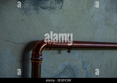 Copper plumbing pipe mounted on textured concrete wall with industrial design Stock Photo