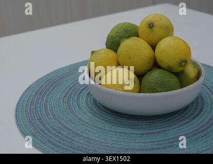 fresh lemons and limes in a fruit bowl on a table Stock Photo
