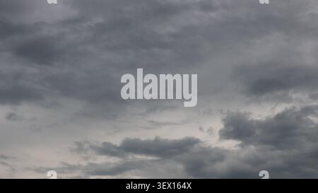 gloomy, overcast sky, covered with dense layers of thunderclouds. The uneven texture of the clouds, Full frame background of a gloomy stormy sky Stock Photo