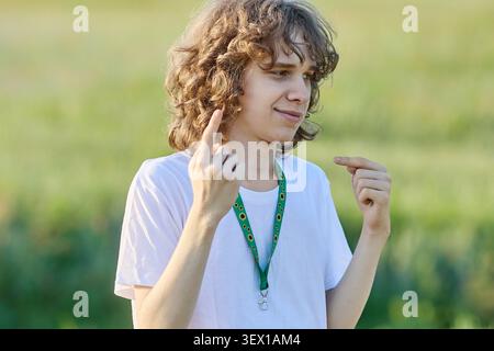 Young man with sunflower lanyard signing in outdoor field Stock Photo