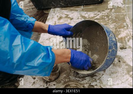 Construction worker mixing cement mortar in bucket at building site Stock Photo