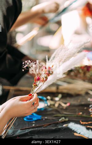 Florist arranging dried flower bouquet with pampas grass in floral workshop Stock Photo