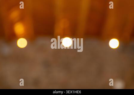 This image showcases a soft, blurred background with three distinct, glowing yellow orbs of light arranged horizontally. Stock Photo