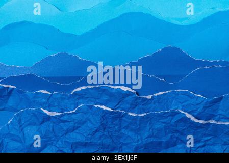 A textured background created from torn layers of blue paper, mimicking the appearance of undulating ocean waves against a serene sky horizon. Stock Photo