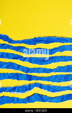 Abstract composition featuring torn strips of blue paper layered over a bright yellow background. Stock Photo