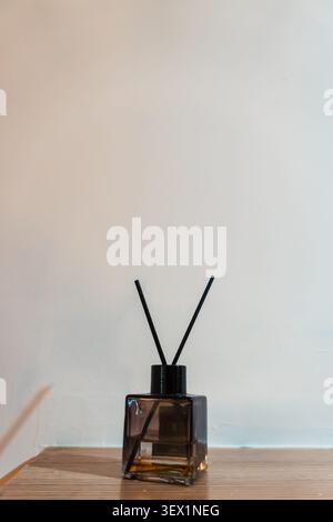 Elegant aromatic diffuser on minimalist wooden table against neutral wall background. Stock Photo
