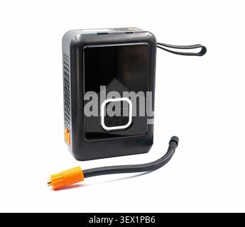 Portable electric compressor with a detachable hose for inflating car, bicycle, and motorcycle tires, on a white background. Stock Photo