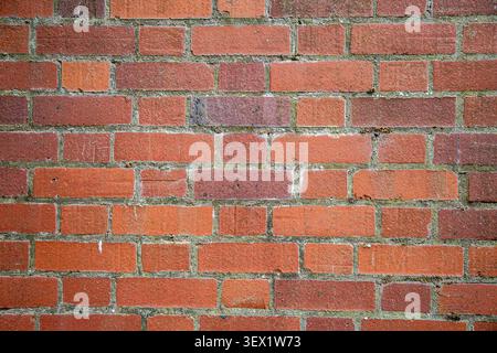 Traditional weathered red brick wall texture featuring aged bricks in shades of red, brown, and muted earthy tones Stock Photo