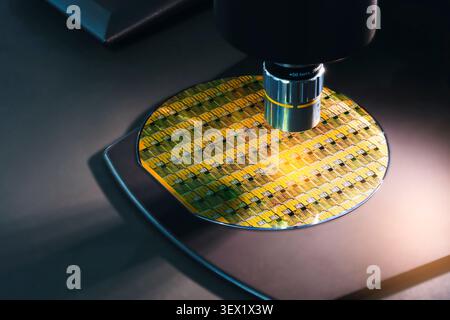 Close-up of a silicon wafer under microscopic inspection. Colorful interference patterns reveal intricate chip structures. Metallic microscope compone Stock Photo