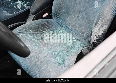 Broken car side window with shattered safety glass on seat. Vehicle damage background illustrating theft vandalism accidents and insurance claims. Stock Photo