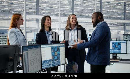 Happy multiethnic engineering team in microchip factory office celebrate project completion, achieving milestones. Cheerful colleagues excited by scientific breakthrough in semiconductor lab, camera A Stock Photo