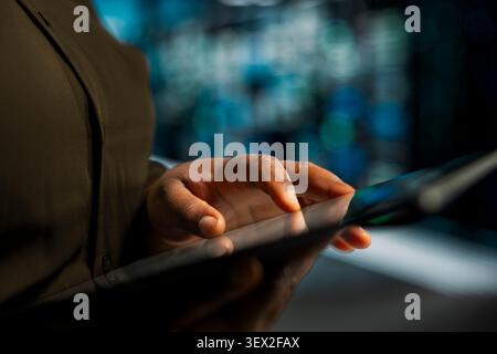 Data center programmer uses a digital tablet in a data center to troubleshoot backend operations and resolve system crashes. Stock Photo