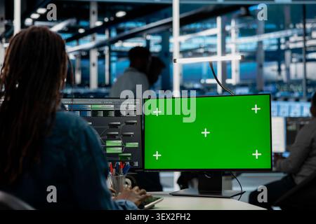 Data center engineer uses a green screen computer in a data center for server operations, screen replacement, and server workflow monitoring. Stock Photo