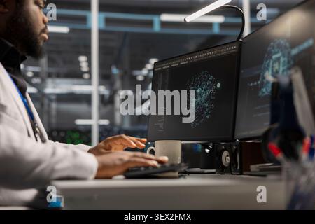IT expert uses a desktop computer in a data center to support supercomputer management and reliable server workflows. Stock Photo