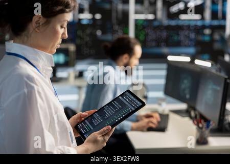 Data center programmer uses a digital tablet in a data center to support failure detection and reliable server workflows. Stock Photo