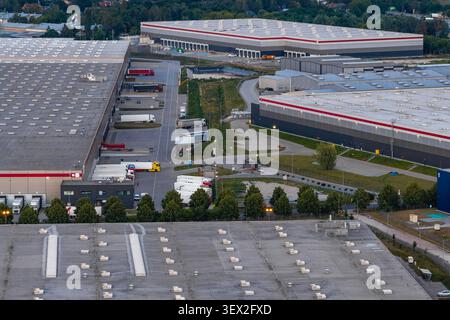 Aerial view of a large distribution center with multiple warehouse buildings, loading docks, and parked semi-trucks in Piorunow, Masovian Voivodeship, Stock Photo