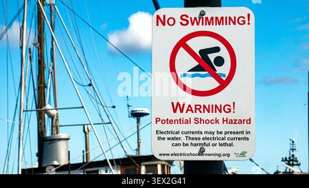 No swimming sign warning of a potential shock hazard in a harbor or marina Stock Photo