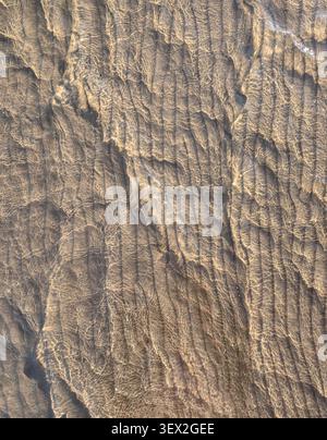 Crystal clear sea water ripple on a sandy beach texture background Stock Photo