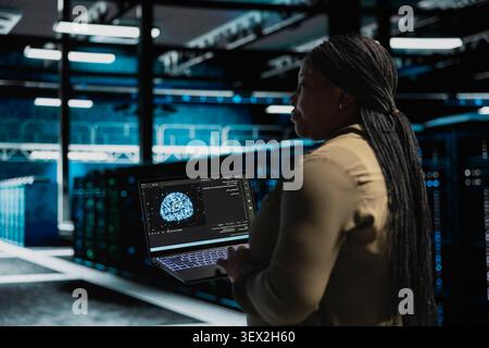 Programmer works with a digital device in a server hub to support artificial intelligence systems. Stock Photo