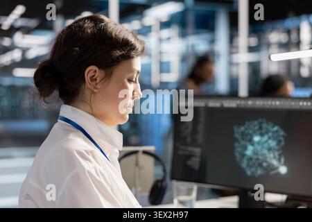Computer scientist reviews performance analytics on a desktop computer in a data center to optimize storage systems and resource use. Stock Photo